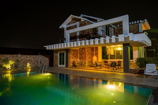 A stunning modern house exterior with a beautifully illuminated swimming pool at night.