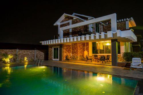 Free A stunning modern house exterior with a beautifully illuminated swimming pool at night. Stock Photo