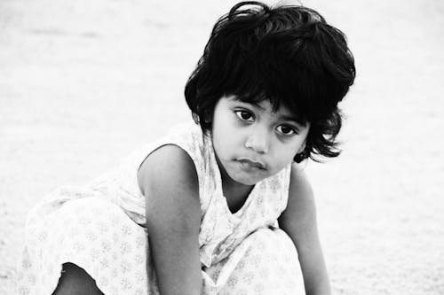 A Grayscale Photo of a Young Girl Wearing White Dress