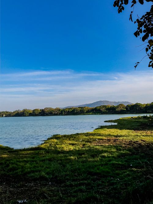 Free Scenic view of a peaceful lake surrounded by greenery under a vibrant blue sky. Stock Photo