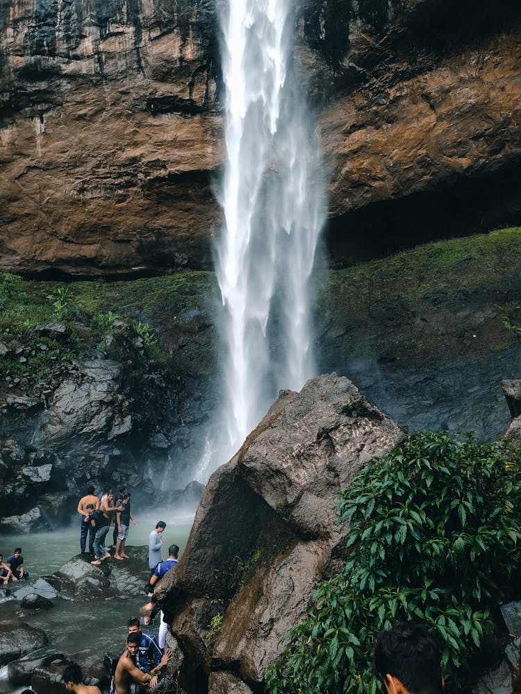 People Standing On Rock Near Waterfalls