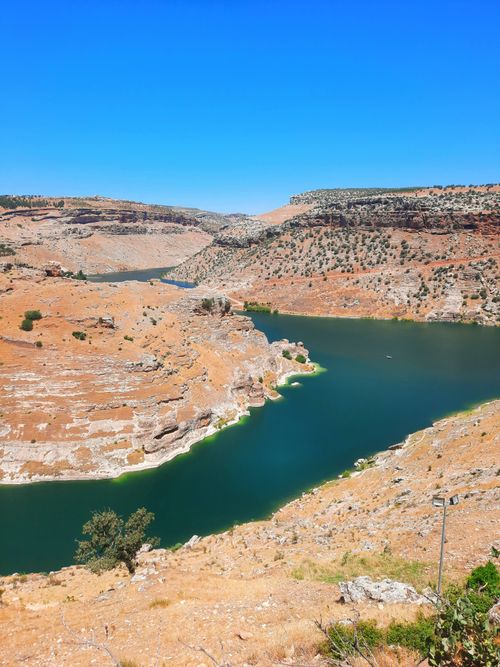 Free A breathtaking view of a river winding through arid hills under a bright blue sky. Stock Photo