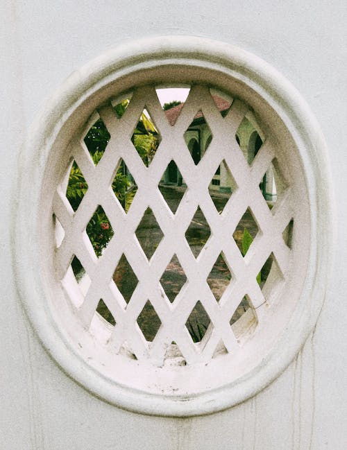 View of a Garden behind a Window with a Pattern in a White Wall 