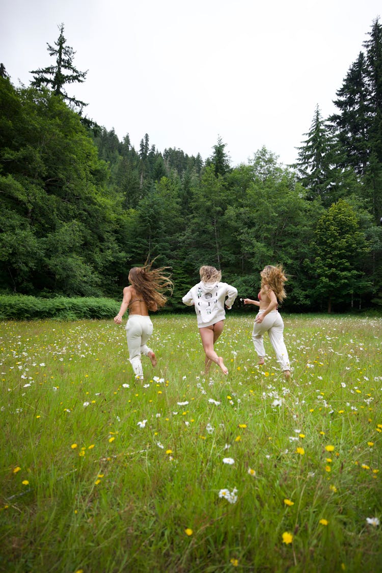 Three Women Running On Flower Field