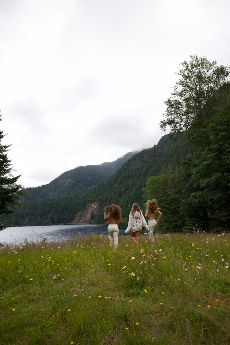 Back View Of Three Women Running On Flower Field