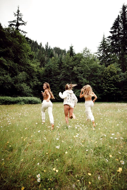 Women Running on Green Grass Field