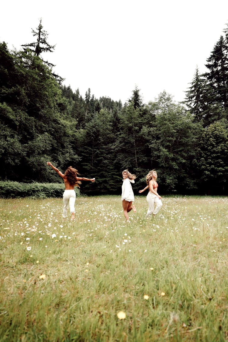 Three Women Running On Flower Field