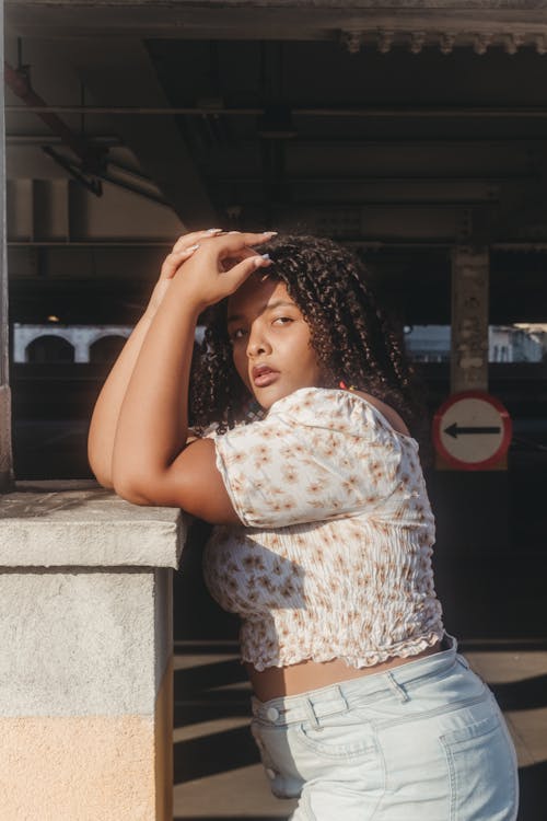 Woman in Floral Top Leaning on Concrete Fence