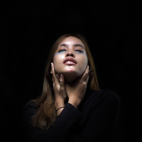 Close-Up Shot of a Woman Touching Her Neck on Black Background