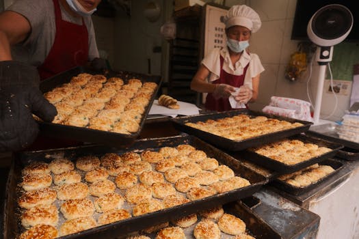 Two bakers preparing fresh sesame pastries in a traditional bakery in Taizhou, Zhejiang, China.