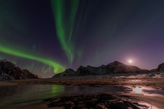 Captivating view of the aurora borealis over mountains and icy landscape at night.