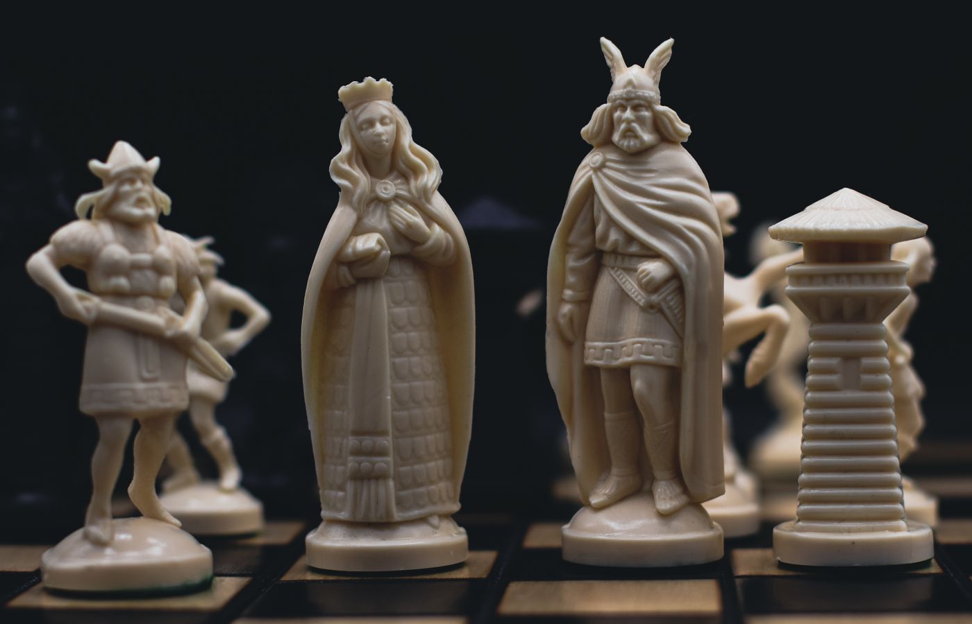 Detailed close-up of intricately carved chess pieces on a chessboard, evoking a medieval theme.