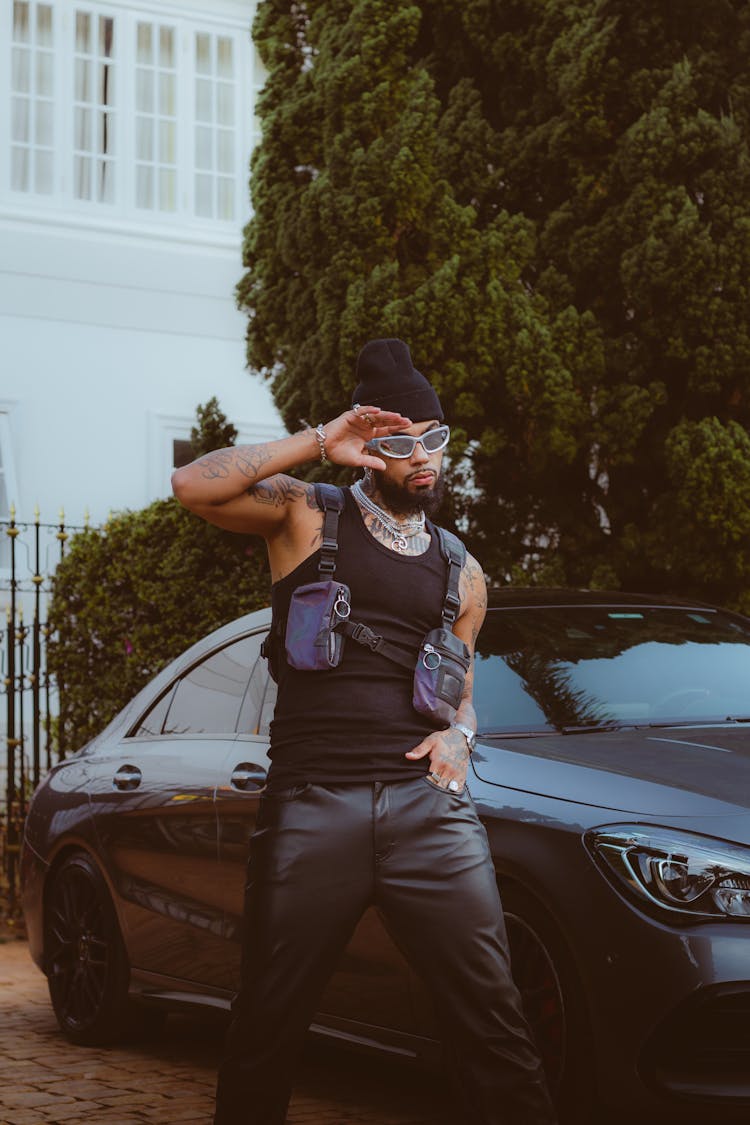 Young Man In Beanie Hat And Sunglasses Posing At Black Car