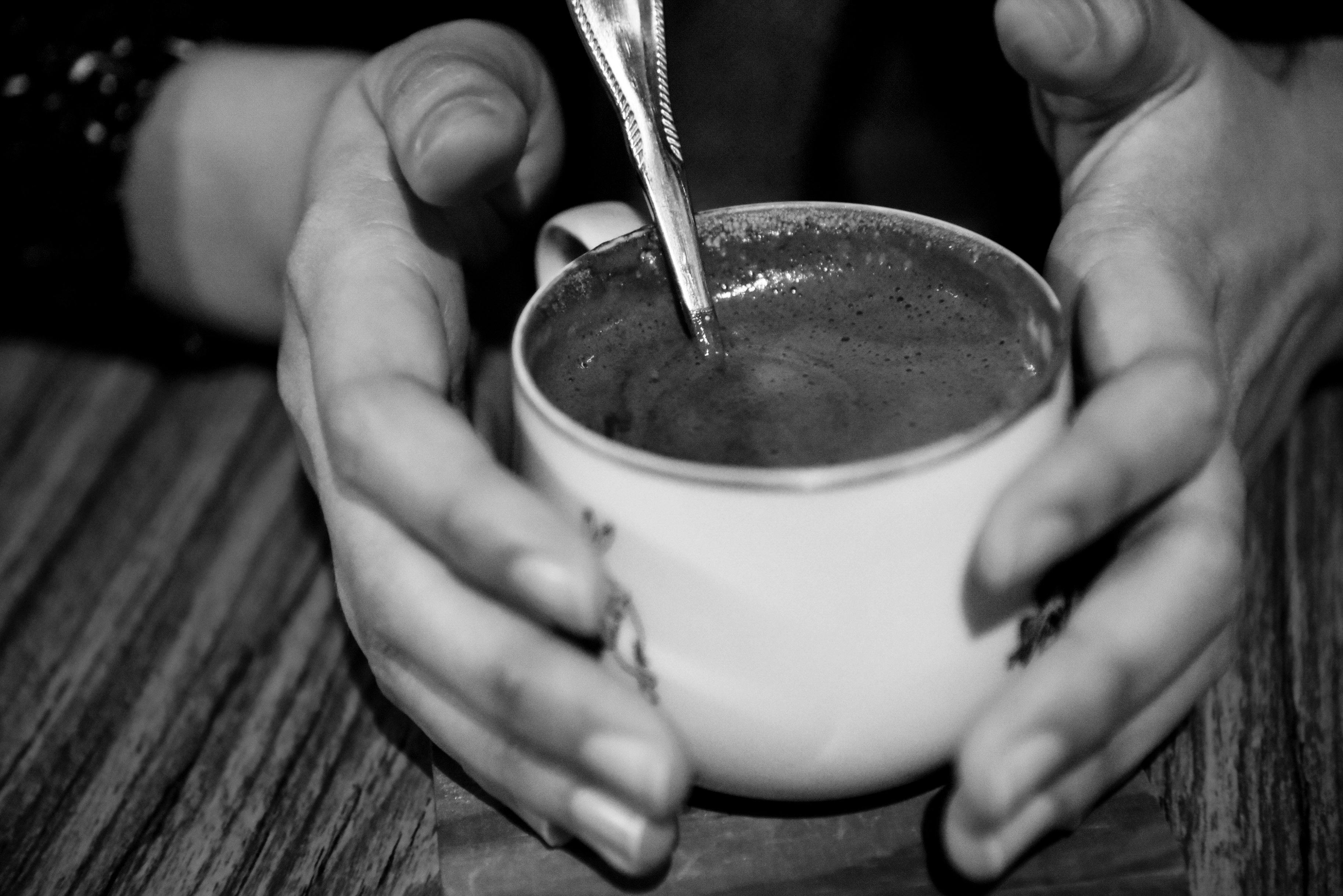 person holding teacup grayscale photo