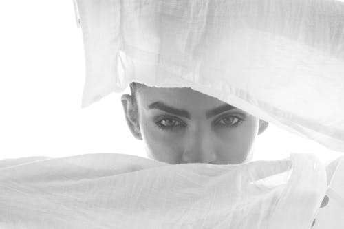 Grayscale Photo of a Woman Behind a White Fabric