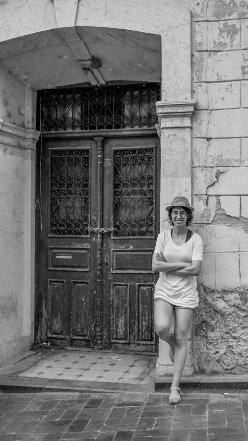 Grayscale Photo of Woman in Shirt and Short Standing Near Door