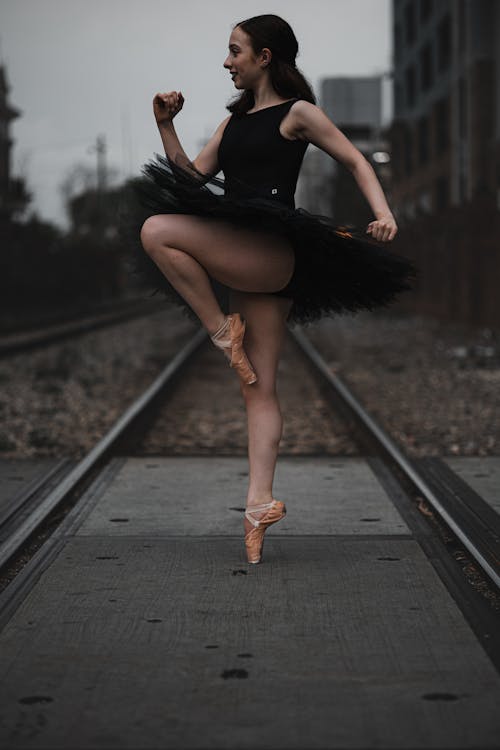 A Woman in Black Tutu Dress Standing on Train Rail