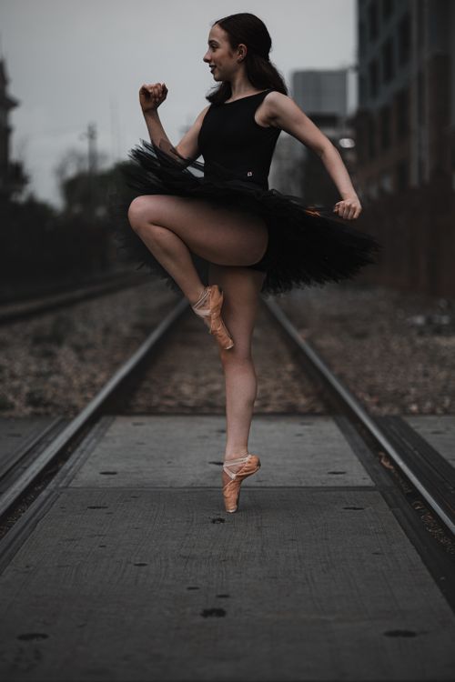 Free A graceful ballerina posing on train tracks, showcasing elegance and strength in an urban setting. Stock Photo