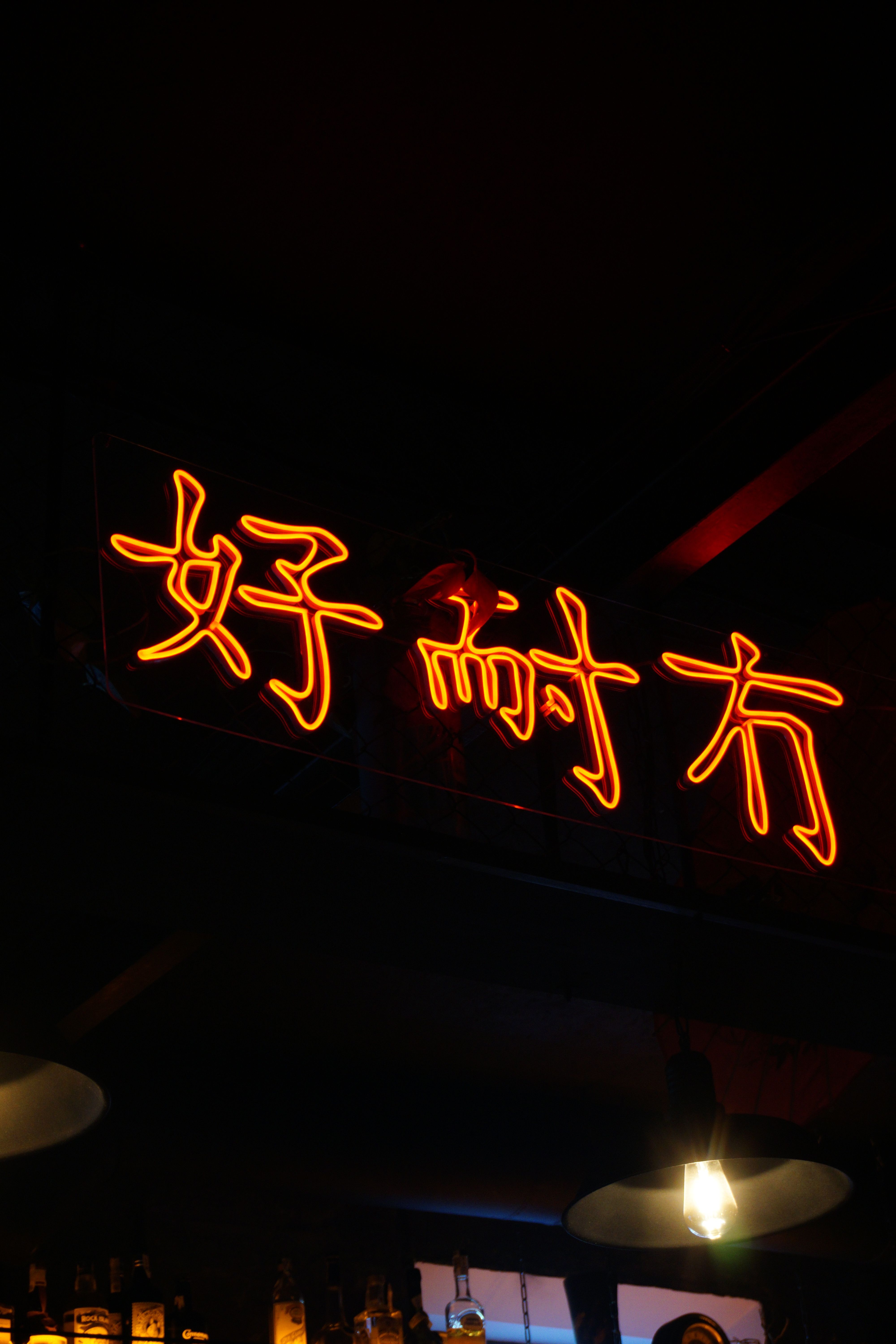 Neon-lit sign with Chinese characters in a cozy Kyiv bar, creating a vibrant ambiance.