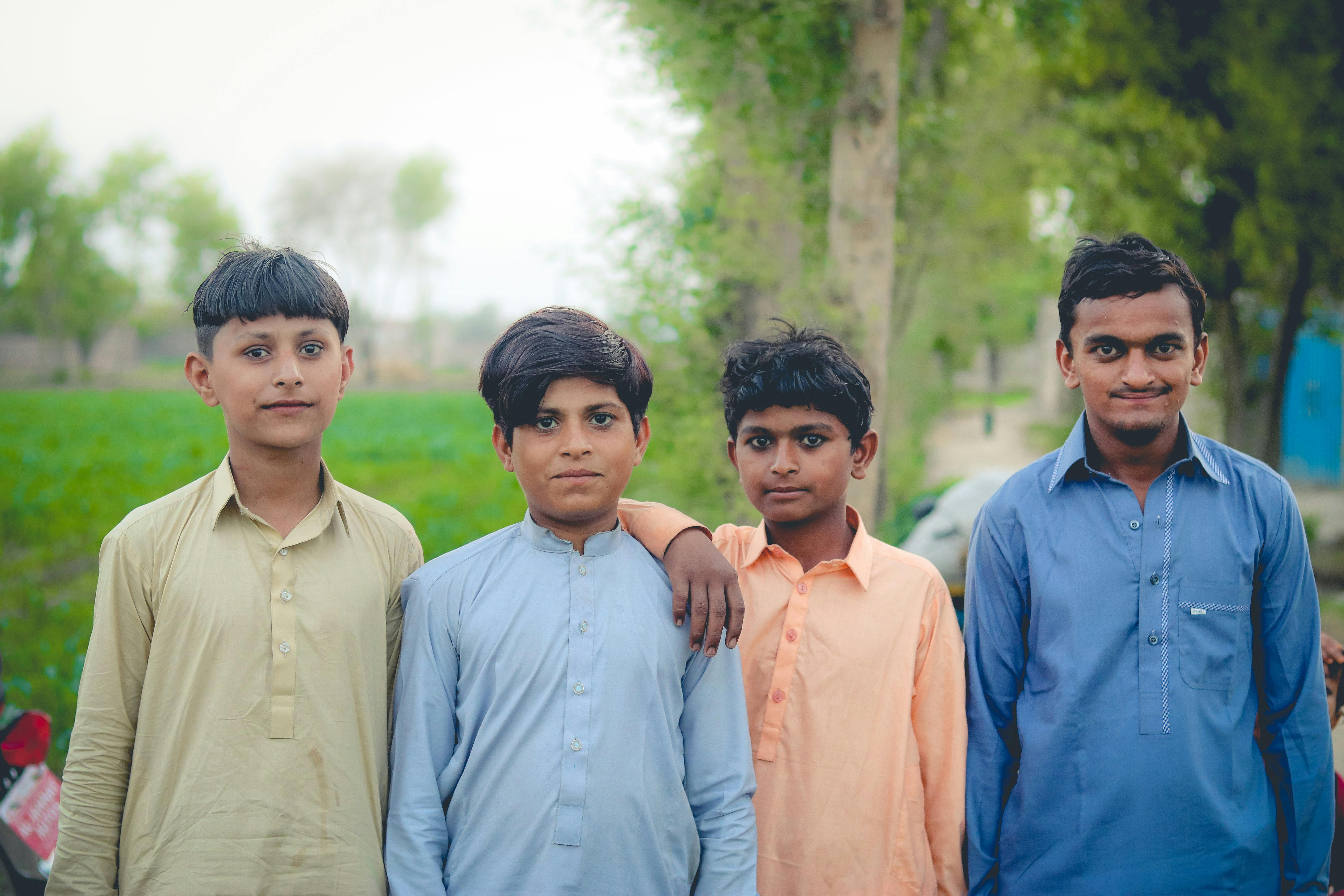 Four boys in traditional clothing standing together outdoors symbolizing friendship and unity.