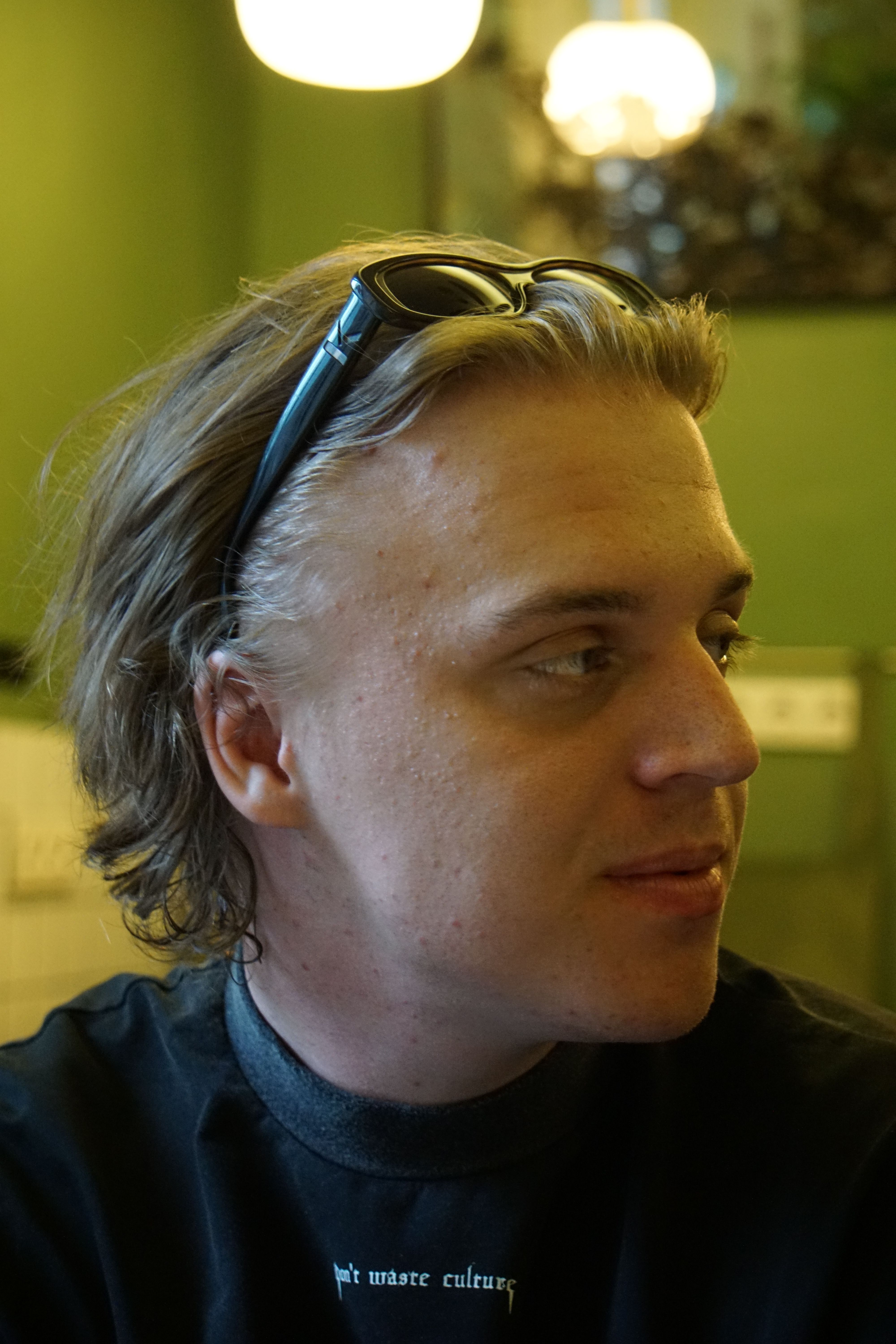 Casual portrait of a man looking away indoors, with a green background.