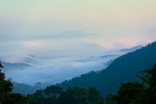 Free Serene mountain view enveloped in misty clouds at sunrise, capturing nature's tranquility. Stock Photo