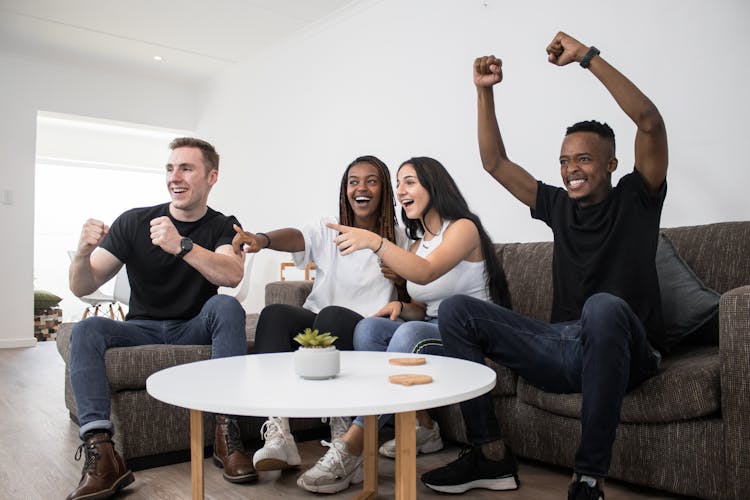 Group Of Friends Sitting On Couch Cheering