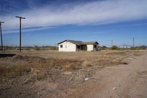 Free Abandoned house in rural Arizona, surrounded by dry grass and utility poles under a blue sky. Stock Photo