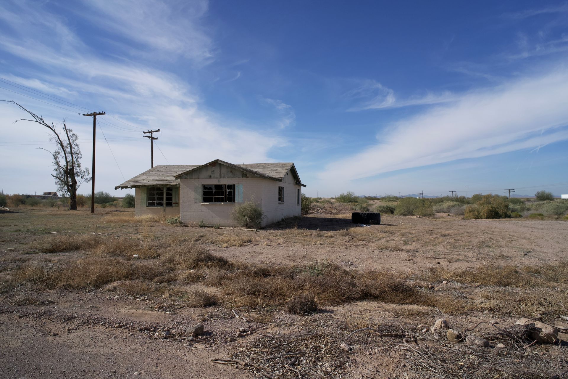 Older single-story house on a dry desert lot