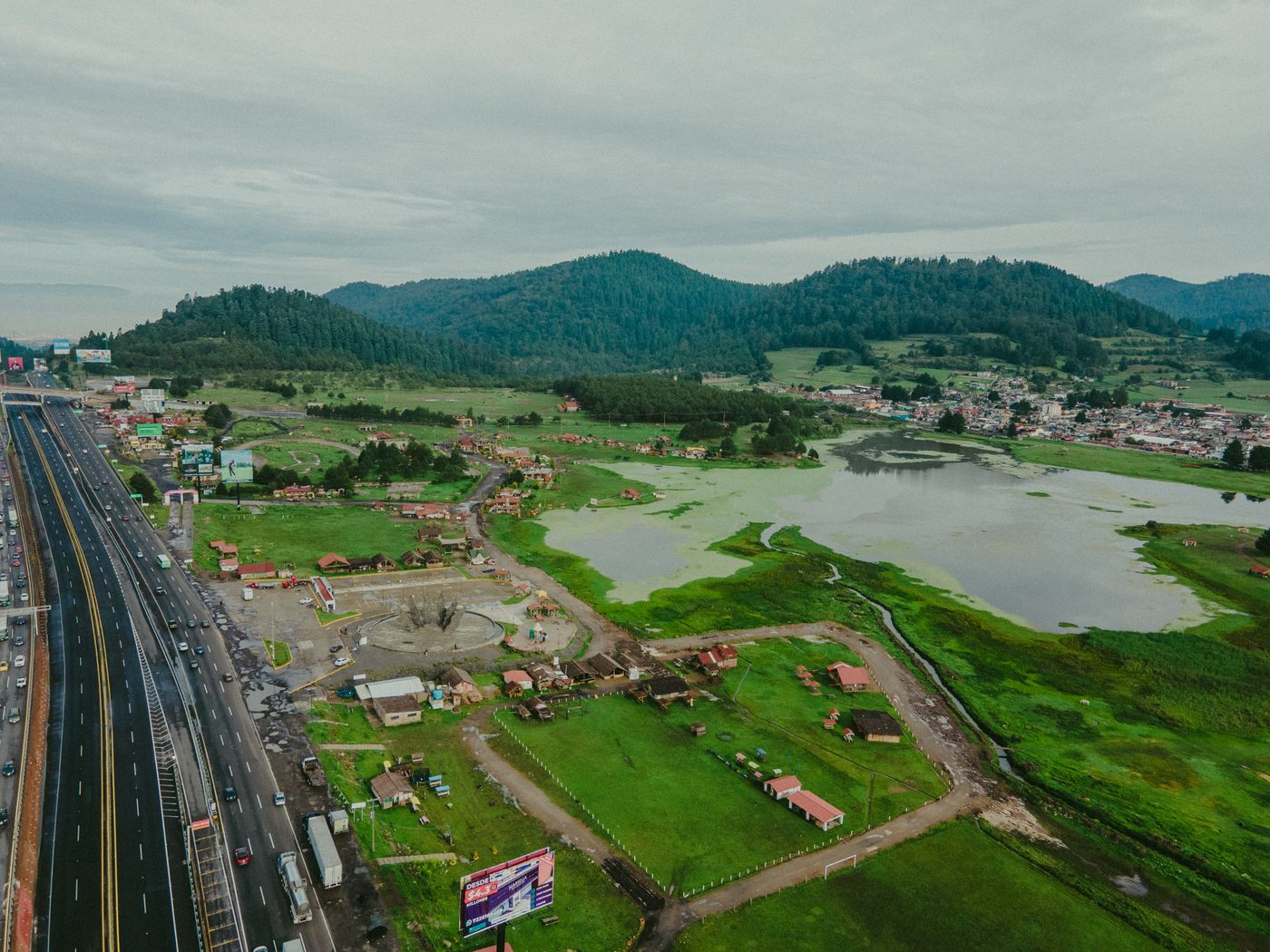 Aerial view of highway, mountains, and lake showcasing nature and transportation.