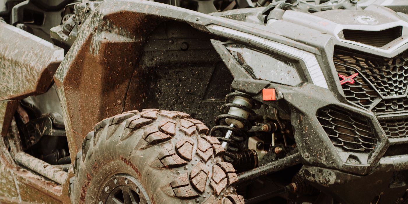 A side-by-side UTV with mud on its tires parked on a dirt trail