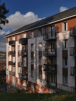 Modern apartment building exterior with shadows cast on facade, showcasing urban residential architecture.
