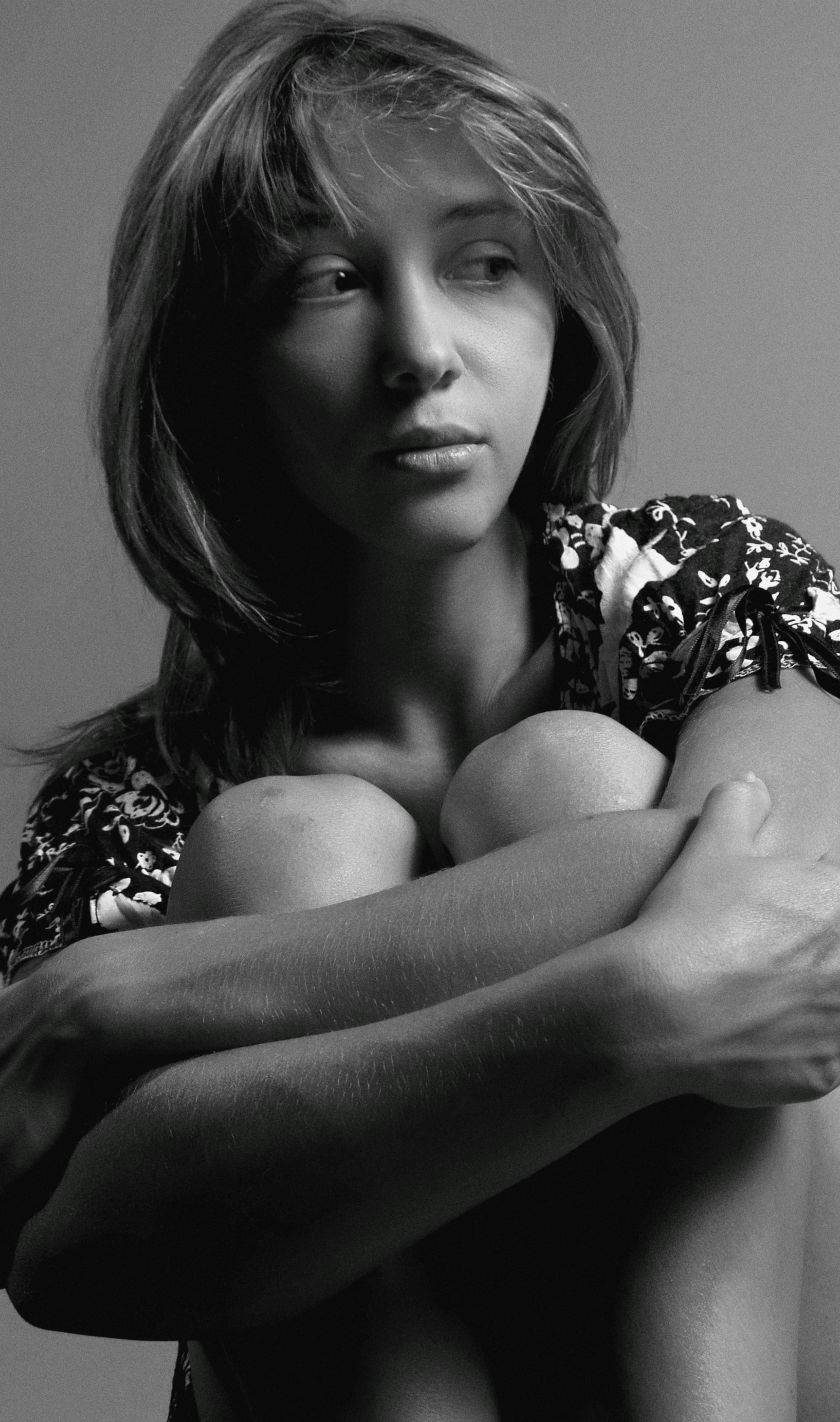 A thoughtful young woman in a black and white portrait, sitting indoors.
