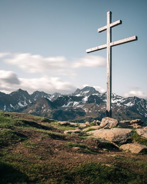 Free Cross on a mountain summit in Tirol, Austria with stunning views of the Alps under a clear blue sky. Stock Photo