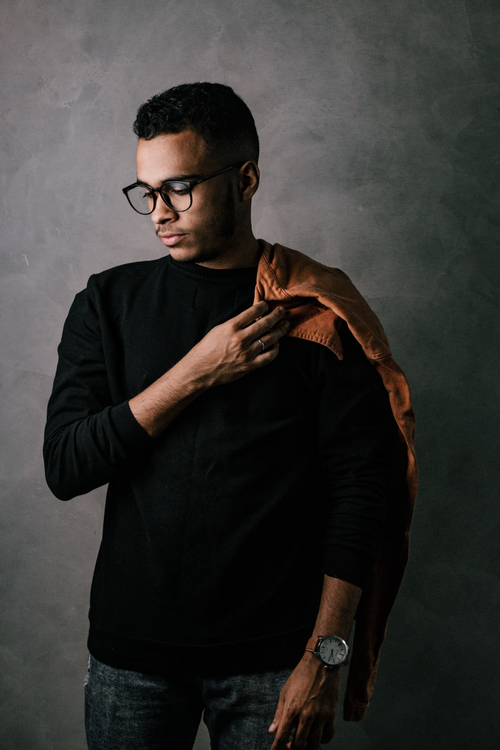 Free Introspective portrait of a young man wearing eyeglasses against a gray background, reflecting style and confidence. Stock Photo