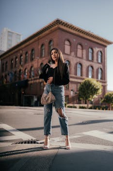 Stylish woman in casual outfit standing at an urban intersection with historic building.