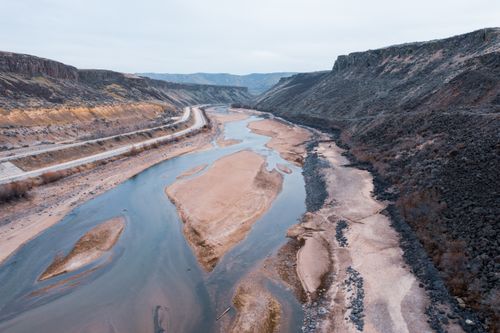 Free Aerial view of a peaceful river flowing through a wide canyon with rocky formations. Stock Photo