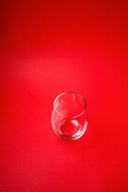 Clear Drinking Glass on Red Surface
