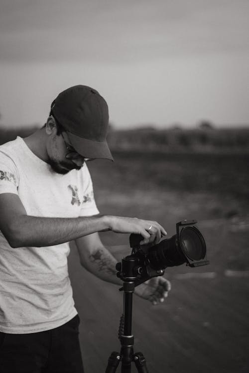 Man in Crew Neck T-shirt and Cap Holding Camera