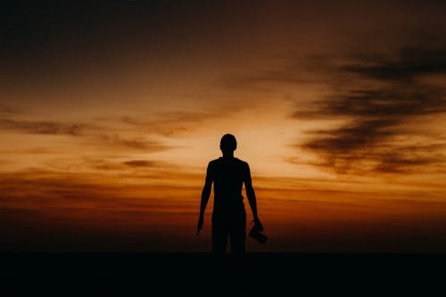 Silhouette of a Person Holding a Camera during Sunset