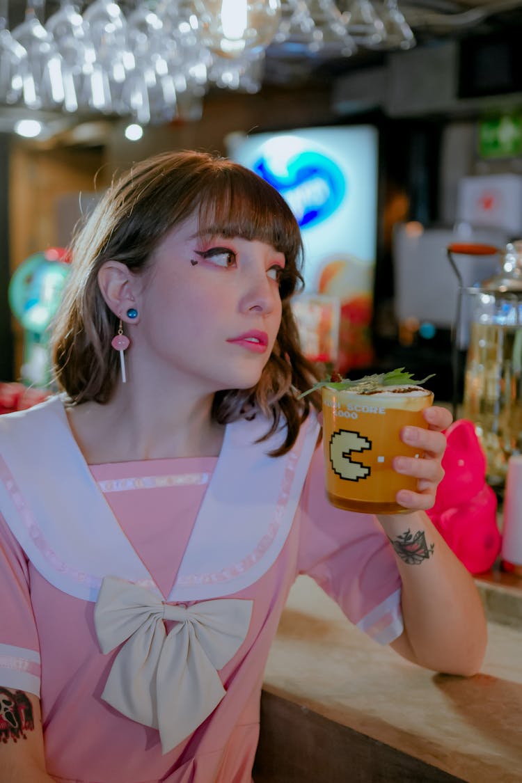 Woman In Pink And White Dress Holding A Drink Looking Sideways