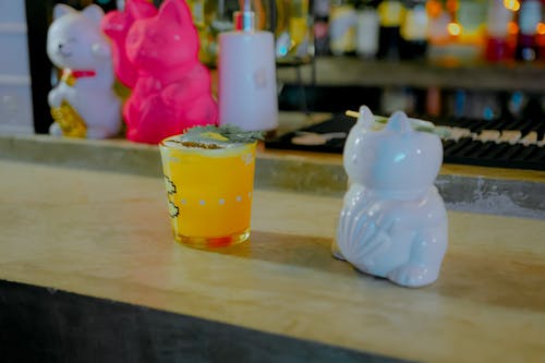 Free Drink on a Bar Counter and Maneki Neko Figurines Stock Photo