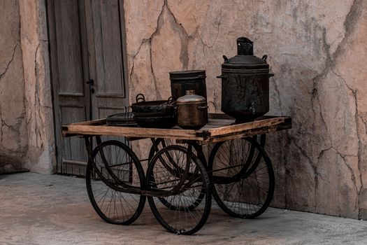 Old wooden cart with metal pots in an urban street of Dubai, showcasing a vintage vibe.