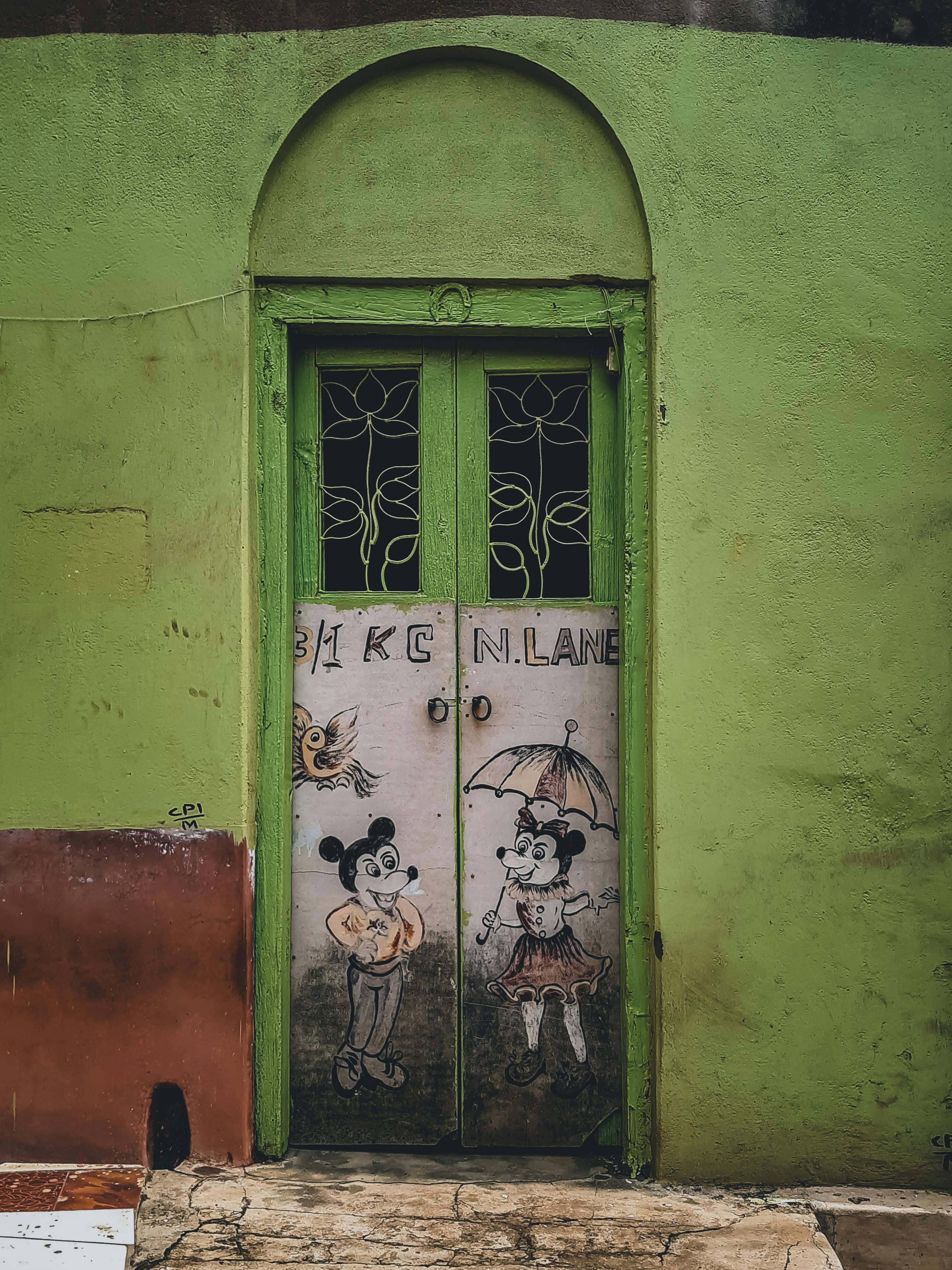 A vibrant green door with playful mural art in Kolkata, India.