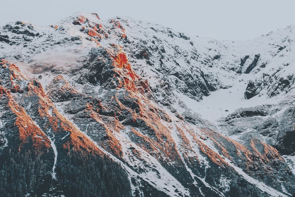 Stunning view of sunlight illuminating snow-capped mountain peaks, perfect for adventure and nature enthusiasts.