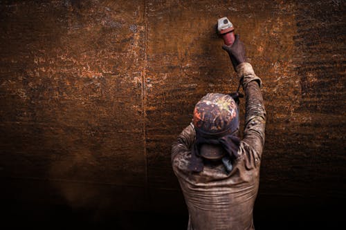 Person Grinding a Rust Metal