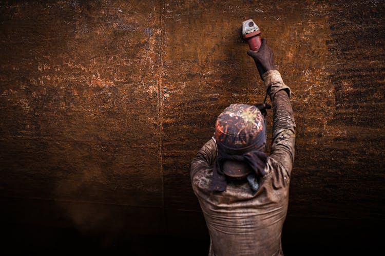 Person Grinding A Rust Metal