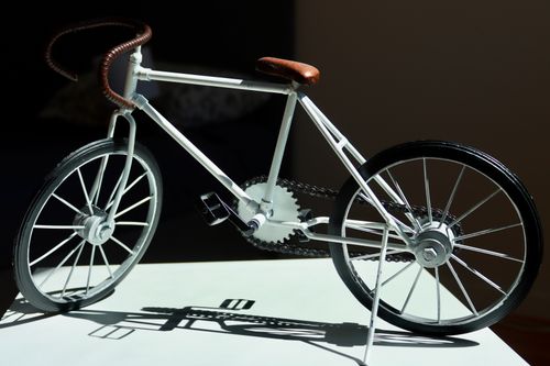 Free A classic miniature bicycle model casting shadows indoors with design details. Stock Photo