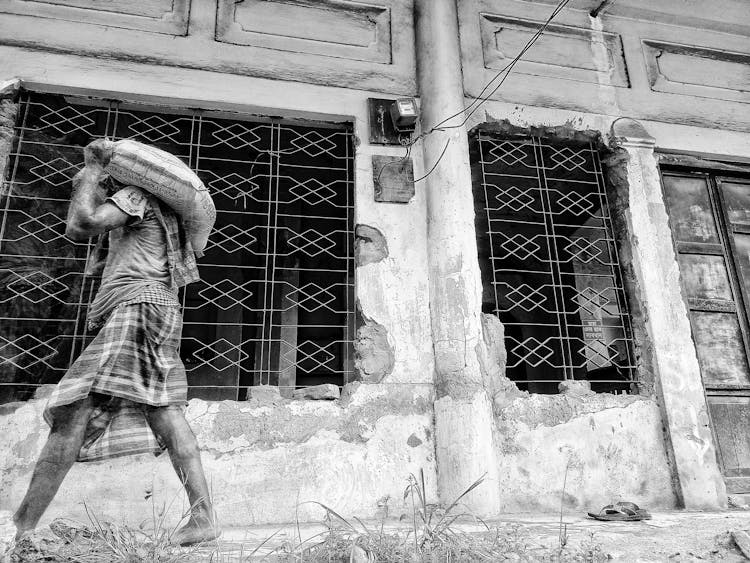 Man Walking With A Heavy Bag Thrown Over His Shoulder 