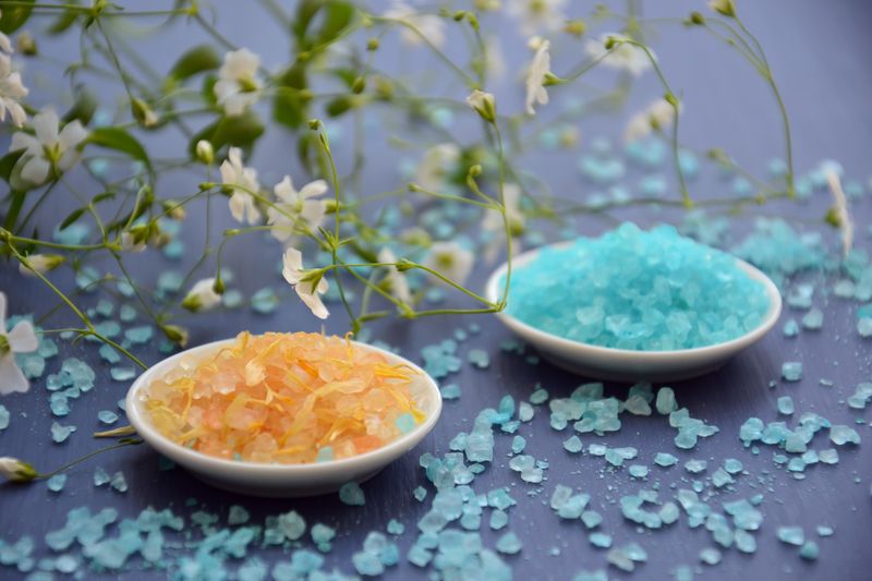 Colorful bath salts in dishes with white flowers